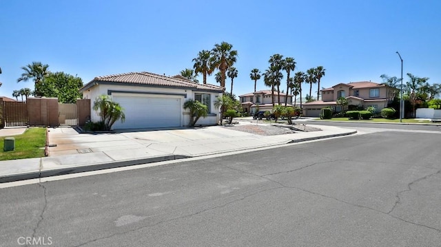 view of front of property featuring an attached garage, concrete driveway, stucco siding, a tile roof, and a gate