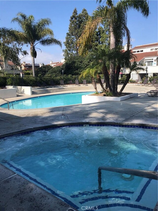 community pool with a hot tub and fence