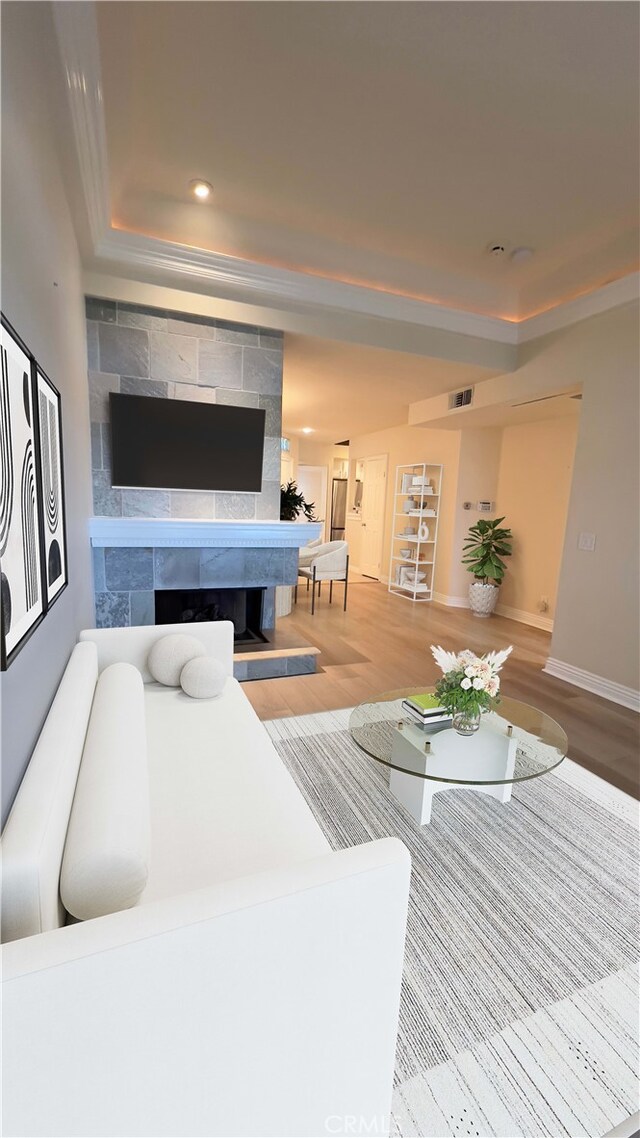 living area featuring wood finished floors, baseboards, crown molding, recessed lighting, and a tile fireplace