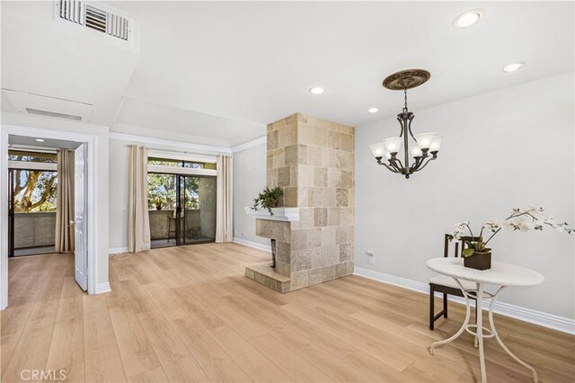 dining space featuring baseboards, light wood-style flooring, recessed lighting, a chandelier, and a fireplace