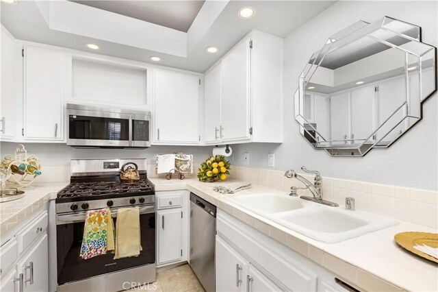 kitchen with stainless steel appliances, a sink, recessed lighting, and white cabinets
