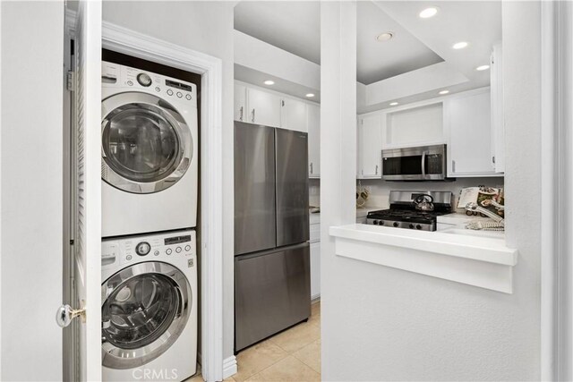 laundry room featuring stacked washer and clothes dryer, recessed lighting, and light tile patterned floors