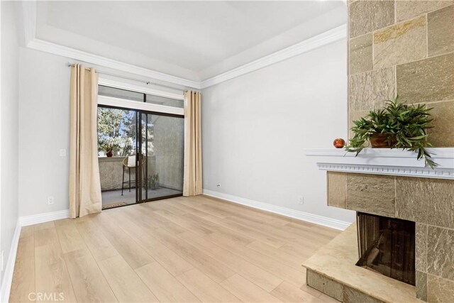 unfurnished living room featuring light wood-type flooring, baseboards, crown molding, and a tile fireplace