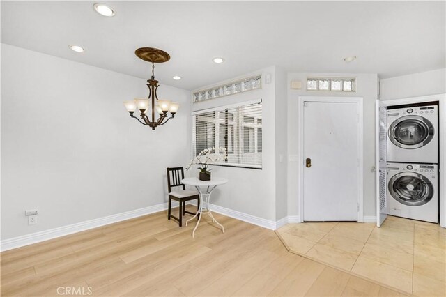 laundry area featuring estacked washer and dryer, a chandelier, recessed lighting, baseboards, and light wood finished floors