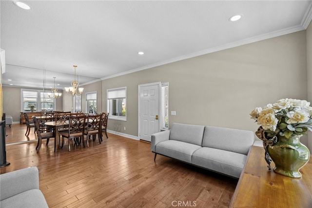 living room featuring a chandelier, baseboards, hardwood / wood-style floors, recessed lighting, and ornamental molding