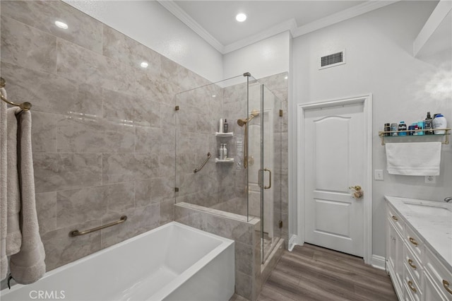 full bathroom with crown molding, a bathtub, a stall shower, vanity, and wood finished floors