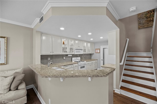 kitchen featuring white appliances, dark wood finished floors, tasteful backsplash, a breakfast bar area, and light stone counters
