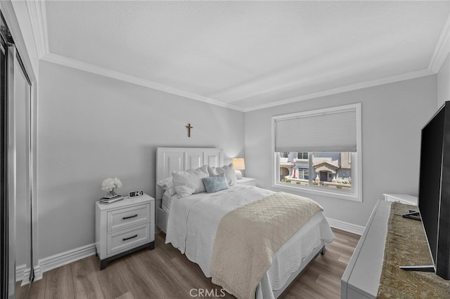 bedroom featuring dark wood-style flooring, crown molding, and baseboards