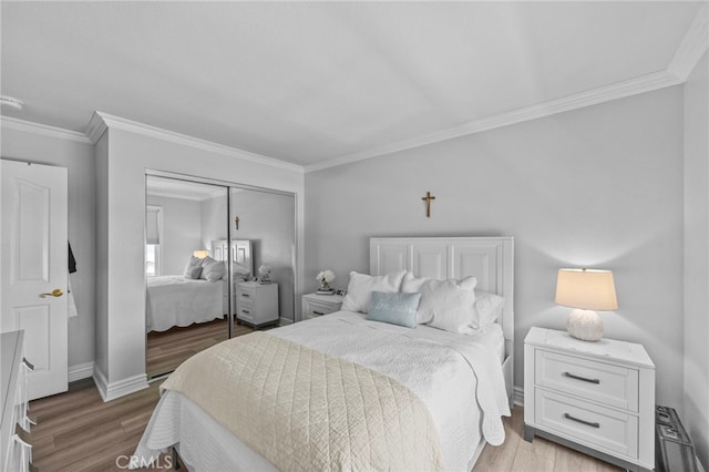 bedroom with light wood-style flooring, ornamental molding, a closet, and baseboards