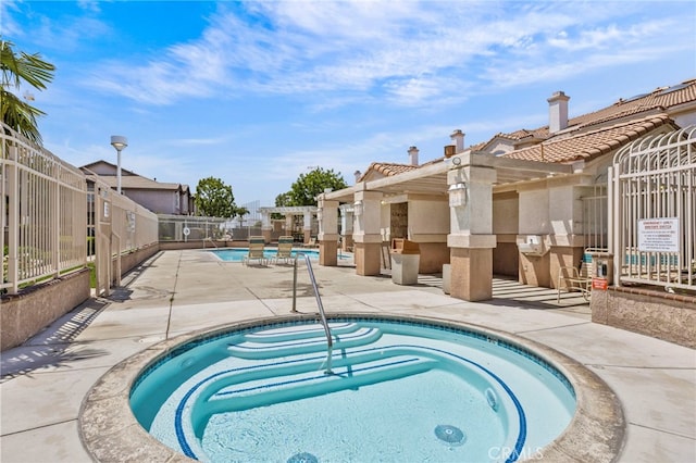 community pool with a community hot tub, fence, a patio area, and a residential view