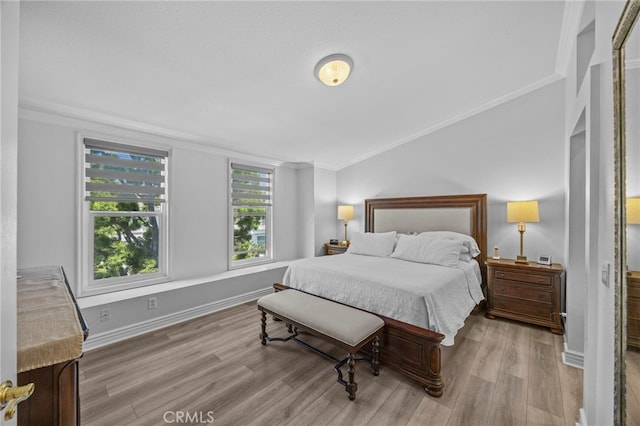 bedroom featuring crown molding, light wood-style flooring, and baseboards