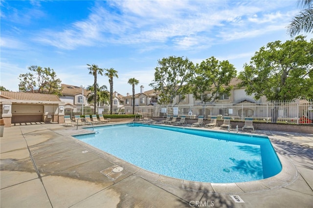 community pool featuring a residential view, fence, and a patio area