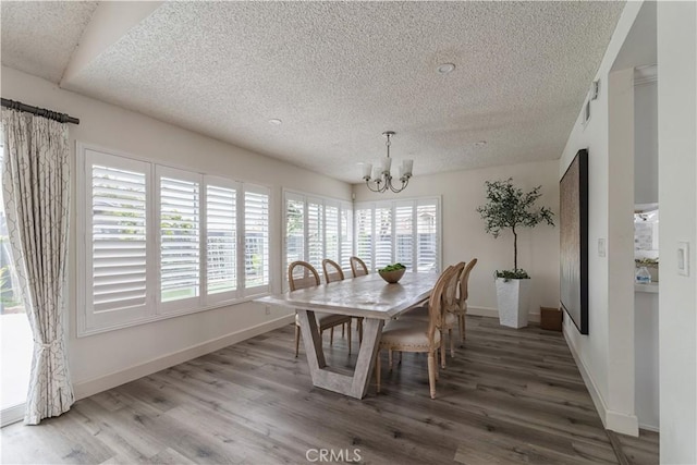 dining room with a chandelier, a textured ceiling, wood finished floors, and baseboards