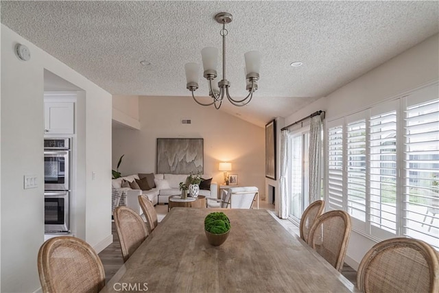 dining area featuring a textured ceiling, vaulted ceiling, a chandelier, and baseboards