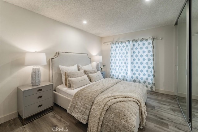 bedroom with wood finished floors, a textured ceiling, baseboards, and recessed lighting