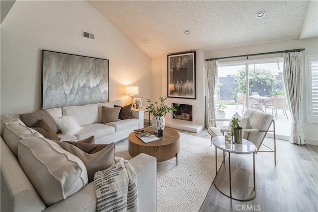 living area featuring light wood-type flooring, a textured ceiling, vaulted ceiling, recessed lighting, and baseboards