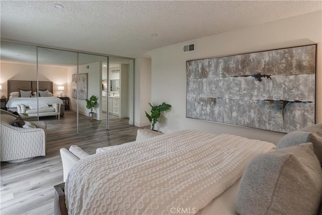 bedroom with a textured ceiling, wood finished floors, and a closet