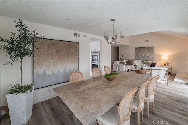 dining area with a chandelier, wood finished floors, and a textured ceiling