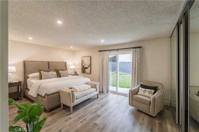 bedroom featuring access to outside, a textured ceiling, recessed lighting, and wood finished floors