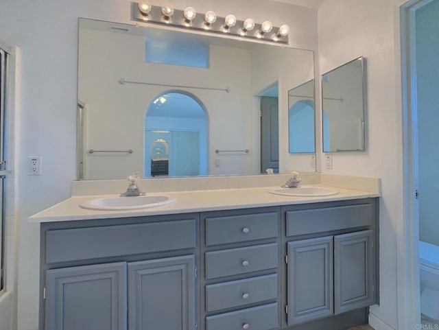 bathroom featuring toilet, a shower with shower door, and double vanity