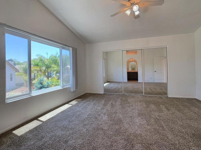 unfurnished bedroom with carpet flooring, lofted ceiling, baseboards, arched walkways, and a closet