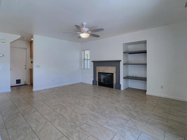 unfurnished living room with built in shelves, a ceiling fan, baseboards, and a tiled fireplace