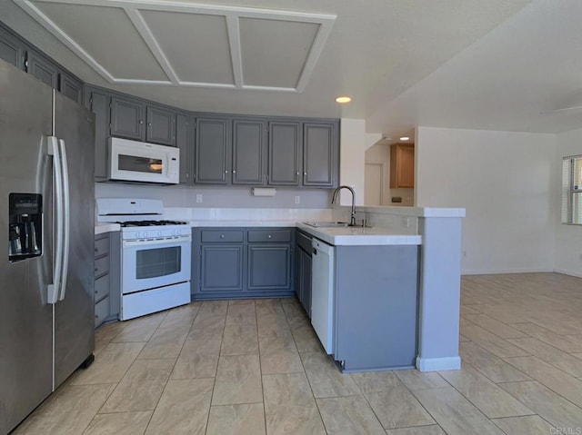 kitchen with white appliances, a peninsula, light countertops, a sink, and recessed lighting