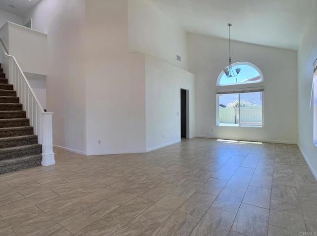 unfurnished living room featuring a high ceiling, stairway, and baseboards