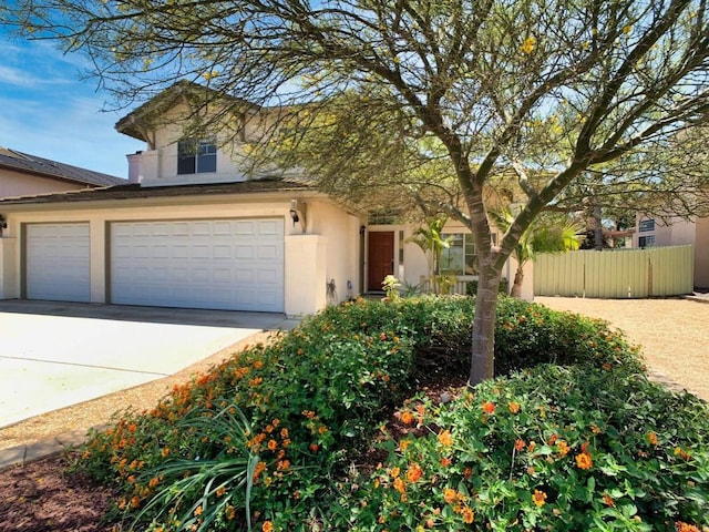 view of front facade featuring stucco siding, driveway, and fence
