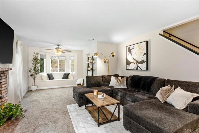 carpeted living area with a ceiling fan and a brick fireplace