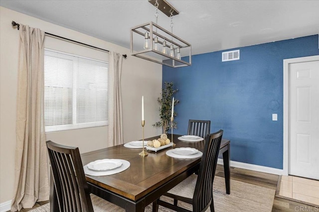 dining space with wood finished floors, a chandelier, and baseboards