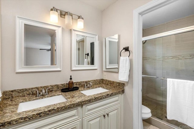 bathroom featuring a shower stall, double vanity, and toilet