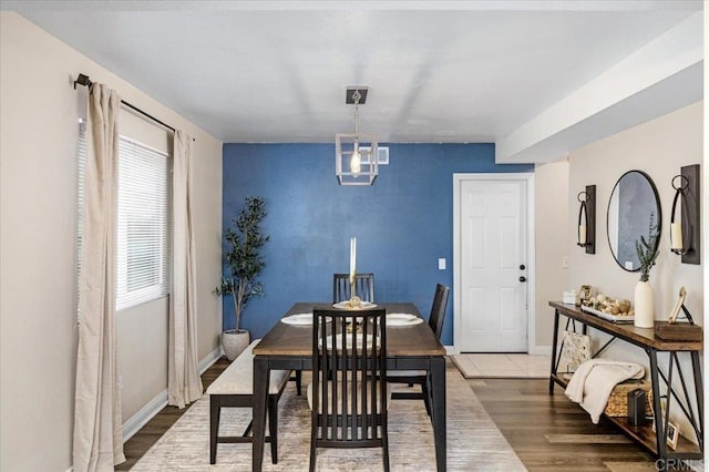 dining area with wood finished floors, an accent wall, and baseboards