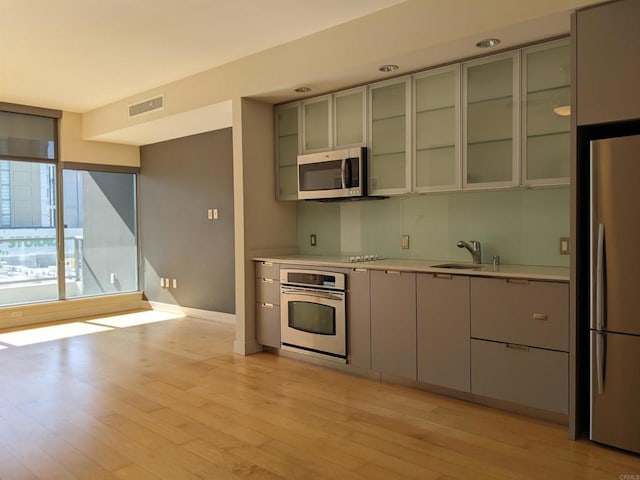 kitchen featuring appliances with stainless steel finishes, light countertops, baseboards, and light wood-style flooring