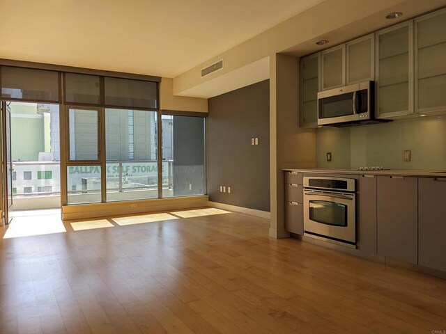 kitchen with appliances with stainless steel finishes, light wood-type flooring, baseboards, and gray cabinets