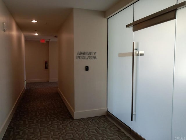 hallway featuring baseboards, dark carpet, and recessed lighting