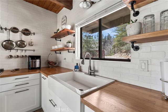 kitchen with open shelves, wooden counters, a sink, wooden ceiling, and white cabinetry