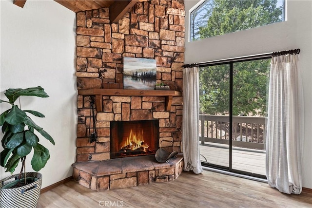 detailed view of wood finished floors, a stone fireplace, and baseboards