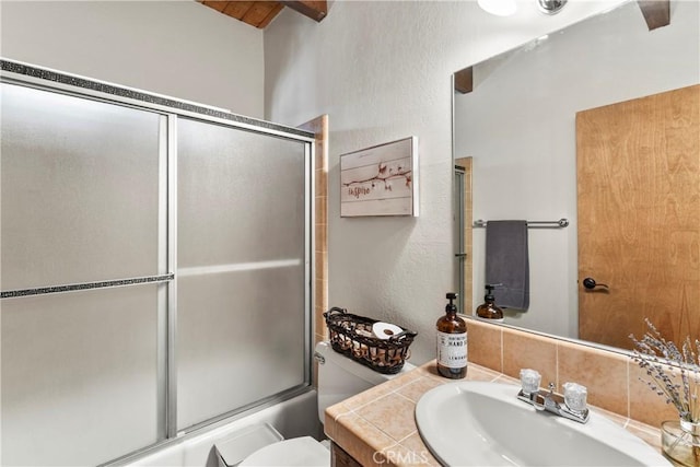 bathroom with toilet, enclosed tub / shower combo, vanity, and beam ceiling