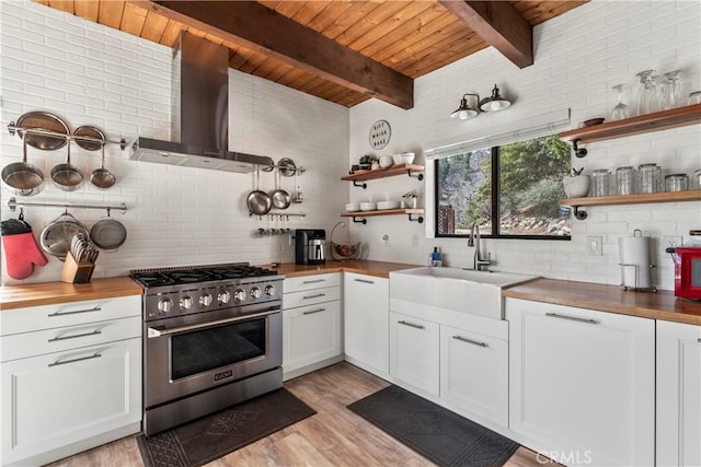 kitchen with high end stainless steel range, wooden counters, wall chimney range hood, open shelves, and wood ceiling