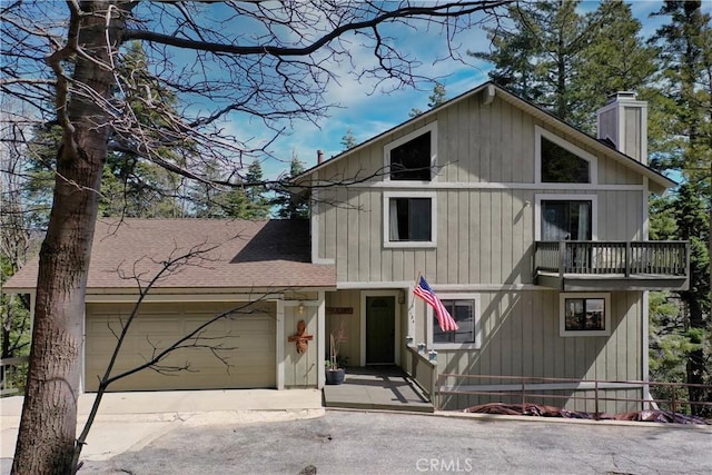 view of front of property with a balcony, an attached garage, driveway, a chimney, and roof with shingles