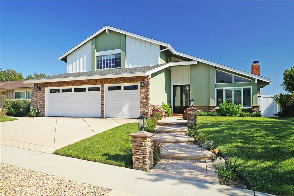 6494 Joshua St, Oak Park, CA 91377 - view of front of home with concrete driveway, an attached garage, a chimney, board and batten siding, and stone siding