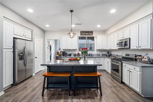 11905 Mendenhall Ln, Whittier, CA 90601 - kitchen featuring stainless steel appliances, white cabinets, dark wood-style flooring, an island with sink, and pendant lighting