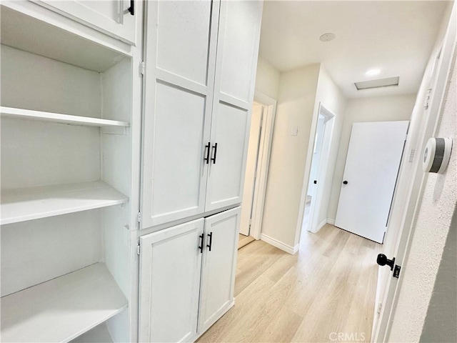 corridor with light wood finished floors, baseboards, and attic access