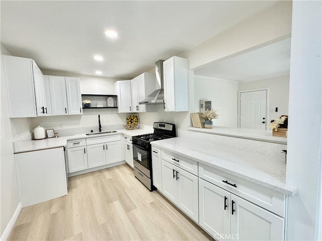 kitchen featuring gas stove, wall chimney range hood, a sink, open shelves, and light wood-style flooring