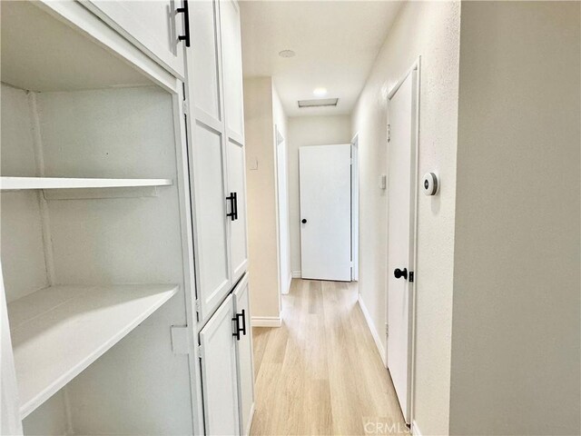 corridor with light wood-style flooring and baseboards