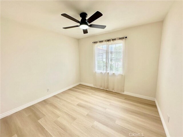 empty room with light wood-style floors, baseboards, and ceiling fan