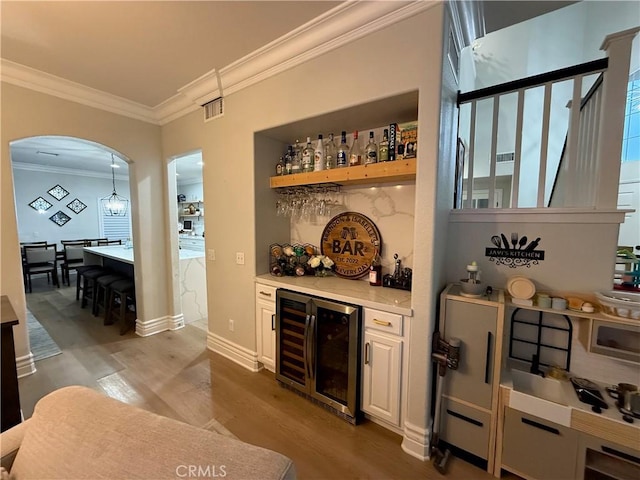 23 Ponte Sonata, Lake Elsinore, CA 92532 - indoor dry bar featuring wine cooler, wood finished floors, arched walkways, crown molding, and baseboards