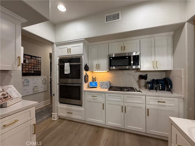 23 Ponte Sonata, Lake Elsinore, CA 92532 - kitchen featuring stainless steel appliances, light countertops, light wood-style floors, white cabinetry, and a textured wall