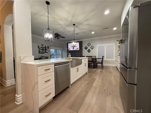 23 Ponte Sonata, Lake Elsinore, CA 92532 - kitchen with appliances with stainless steel finishes, a sink, ornamental molding, white cabinetry, and light wood finished floors